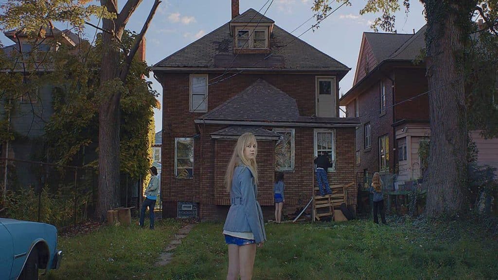 A girl looking back at the camera with a house in the background.