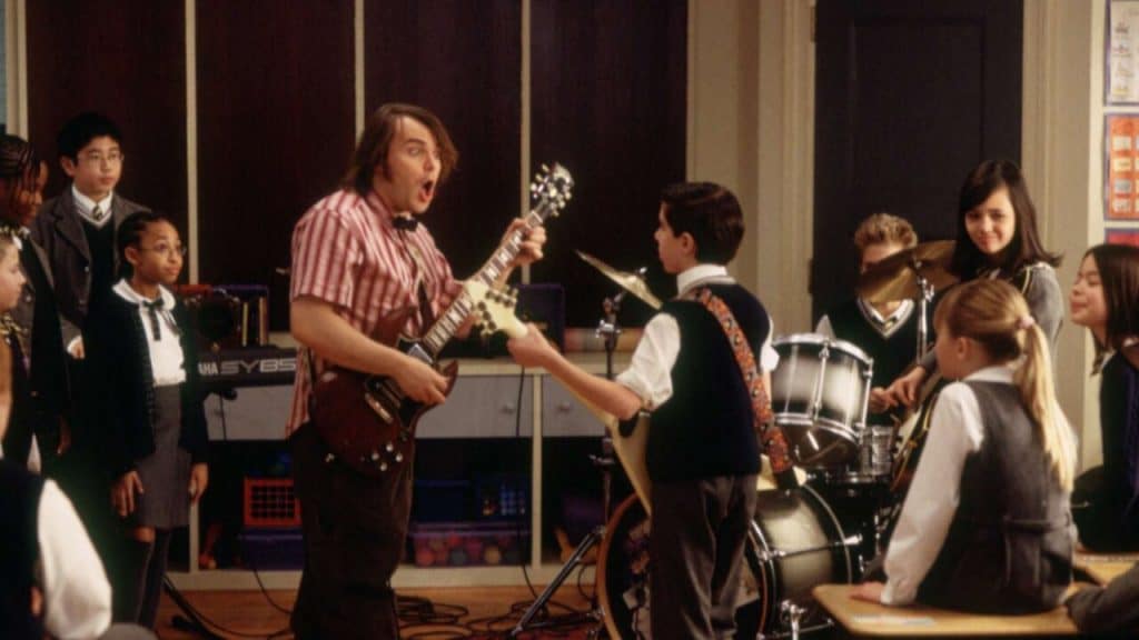 A picture of Jack Black and different kids practicing music.
