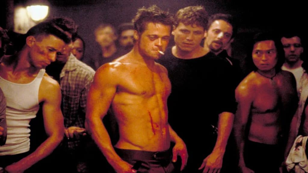 Brad Pitt smoking a cigarette surrounded by different men.