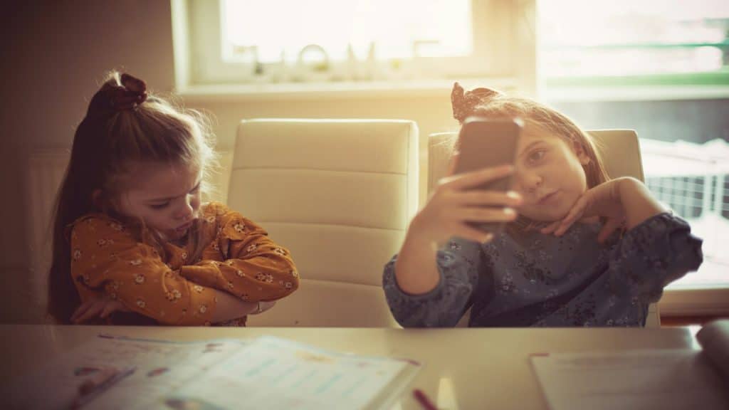 Little girl looks sad while other girl takes a selfie