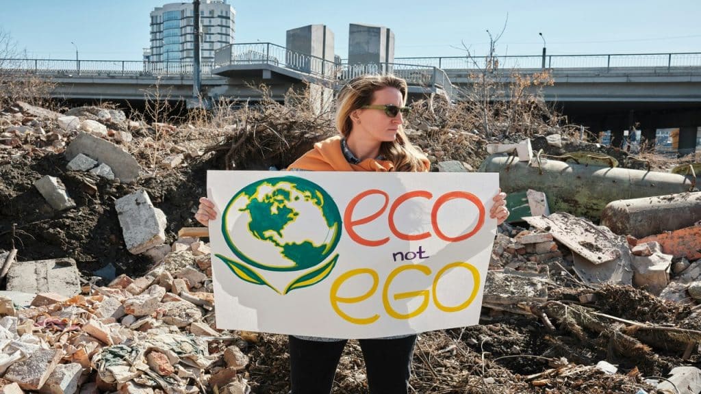 A woman holding a sign saying “eco, not ego”