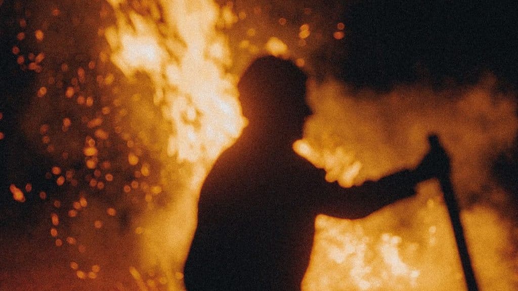 A picture of a man beside a fire