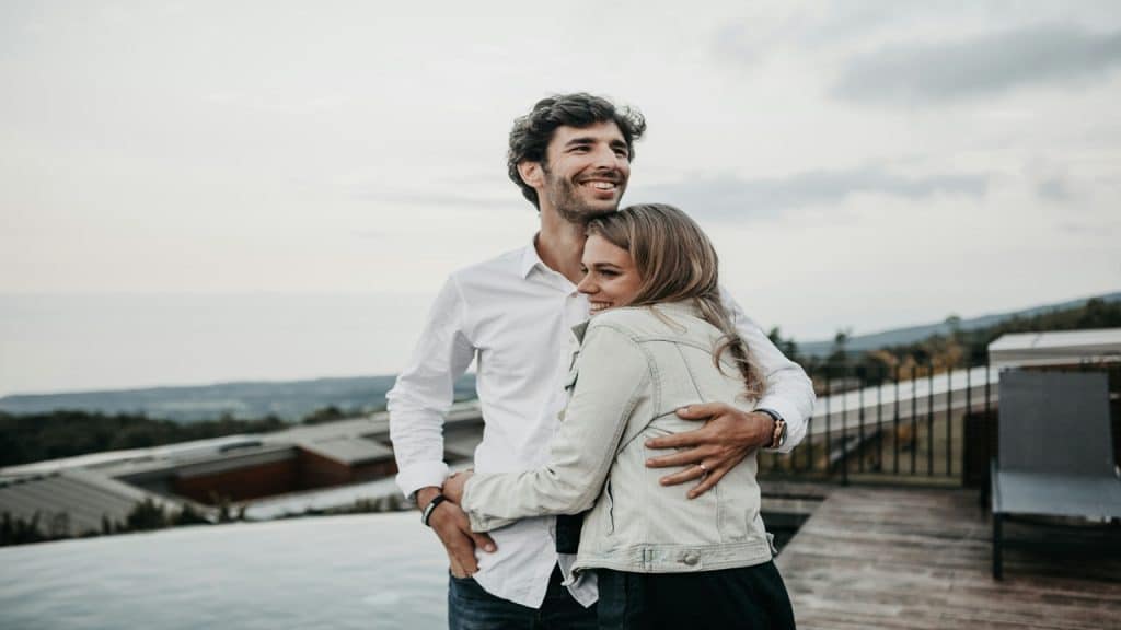 A couple smiles as they hug each other.