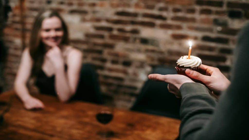 A partner joyfully celebrates a loved one’s win by holding a cupcake with a candle.