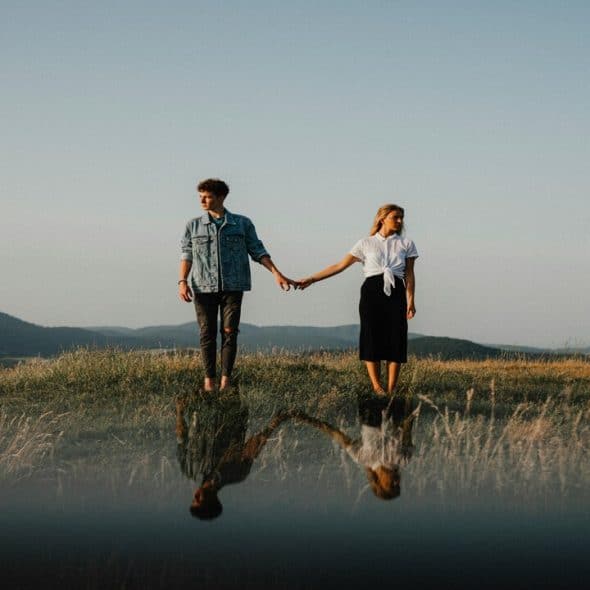 A couple holding hands but looking away from each other.