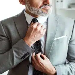 A man with beard wearing a grey suit.