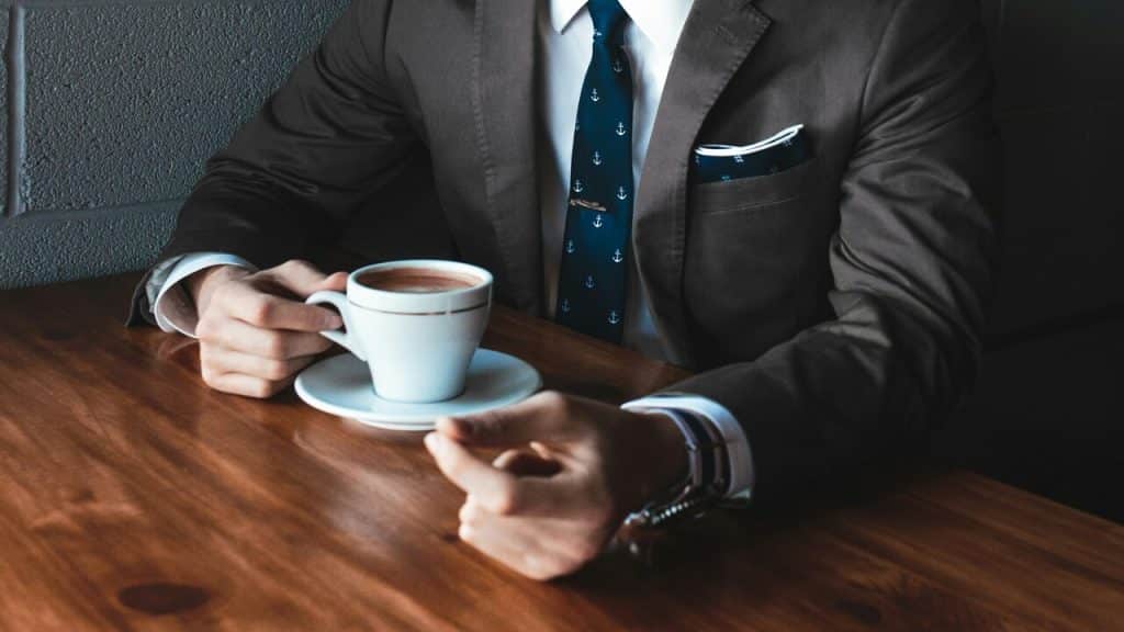 A man wearing a suit and holding a cup of coffee.