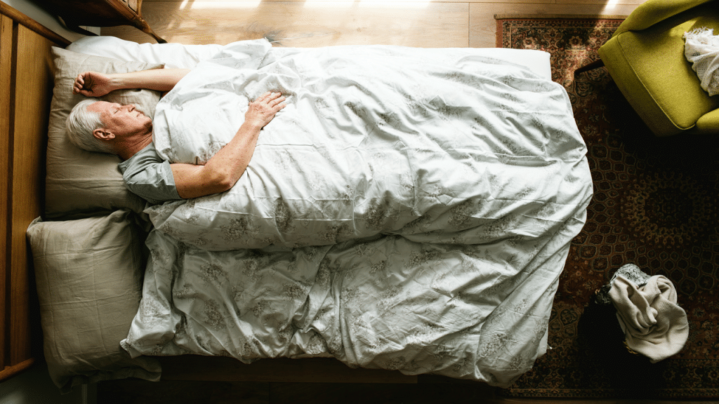 An older man sleeping peacefully in a cozy bed. 