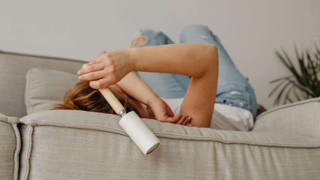 A woman lying on a bed and holding a lint remover.