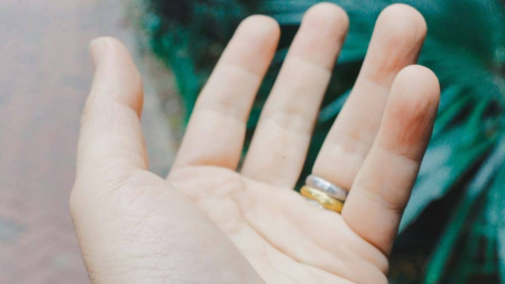 A man is wearing a gold and silver ring on his middle finger.