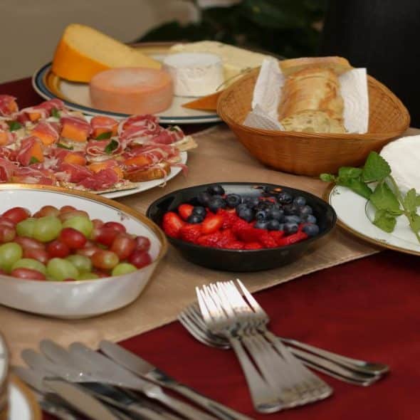 A table set with cheese, fruit, bread, and appetizers.