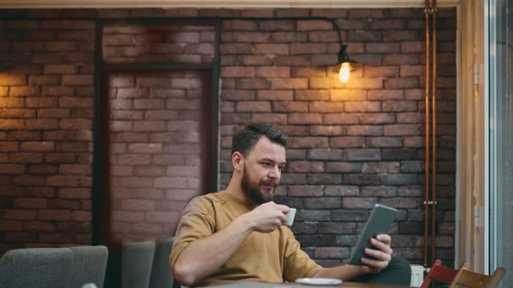 Man using a dating app on his phone while seated at a café table.