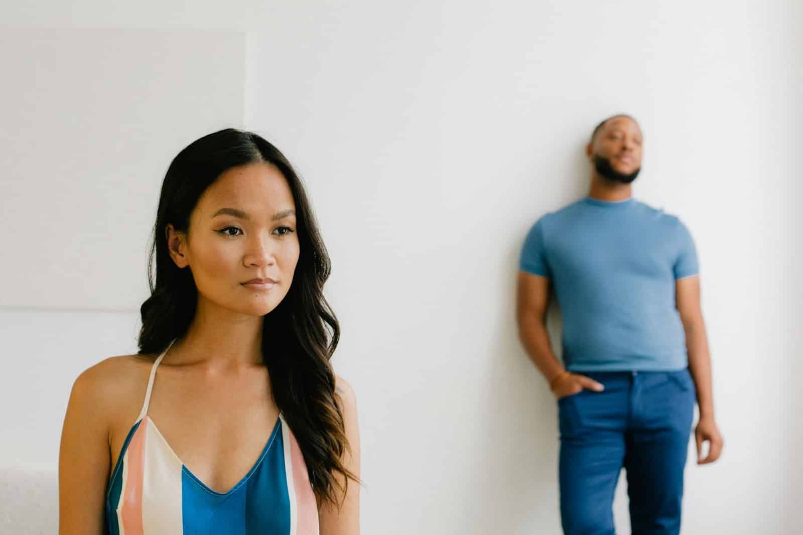 A man standing at the back of woman.