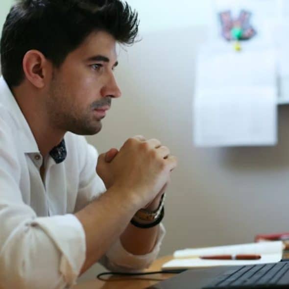 Man reflecting on personal growth while looking at his laptop at home