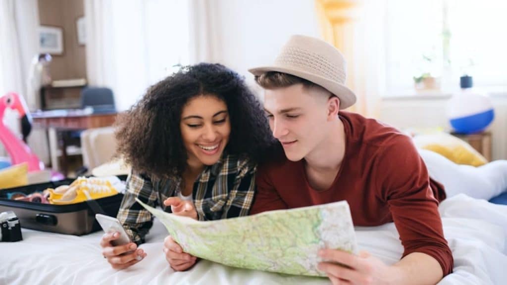 Couple planning a trip together using a phone and a map at home