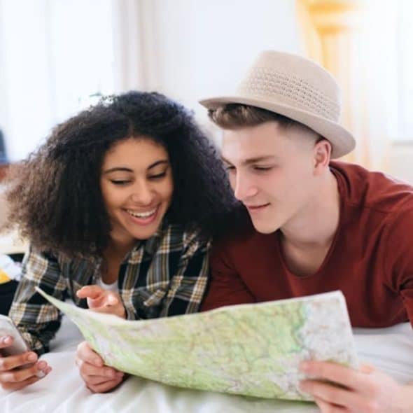 Couple planning a trip together using a phone and a map at home