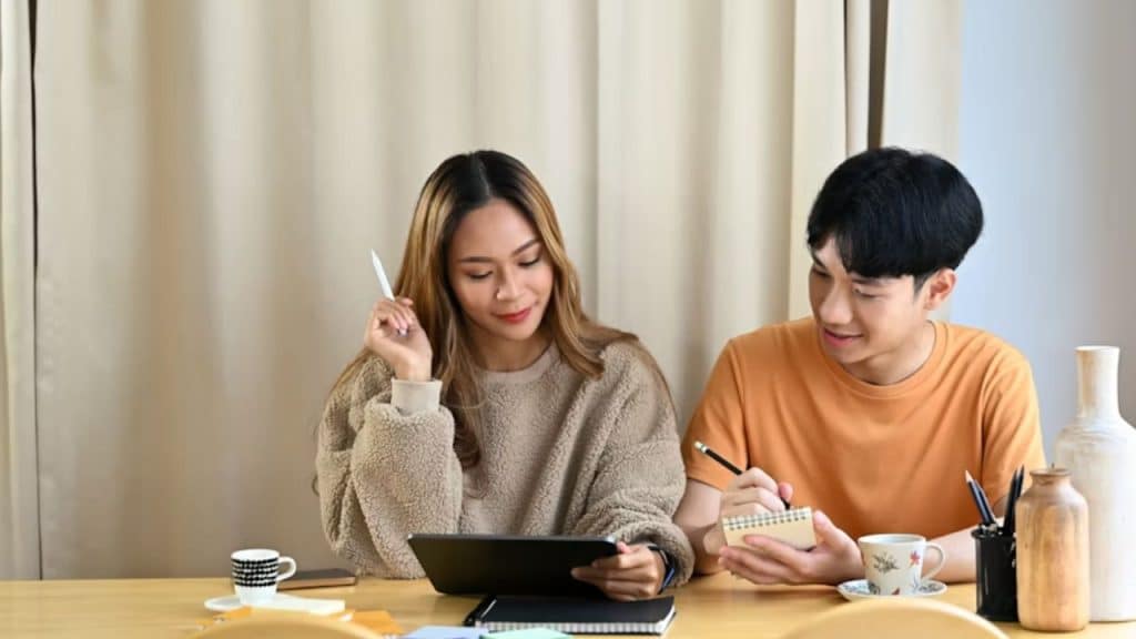 Couple organizing time off with devices and a shared calendar at a table