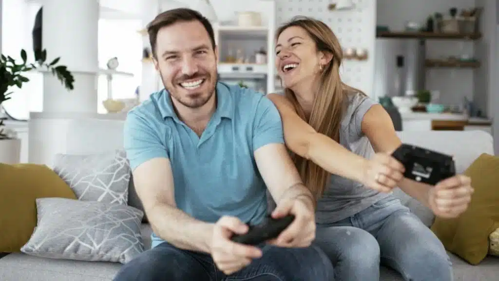 Couple laughing together while sitting on the couch playing a  game
