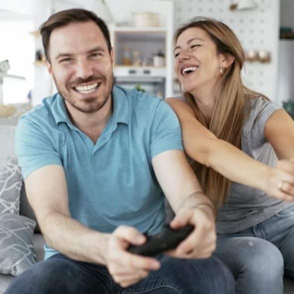 Couple laughing together while sitting on the couch playing a game