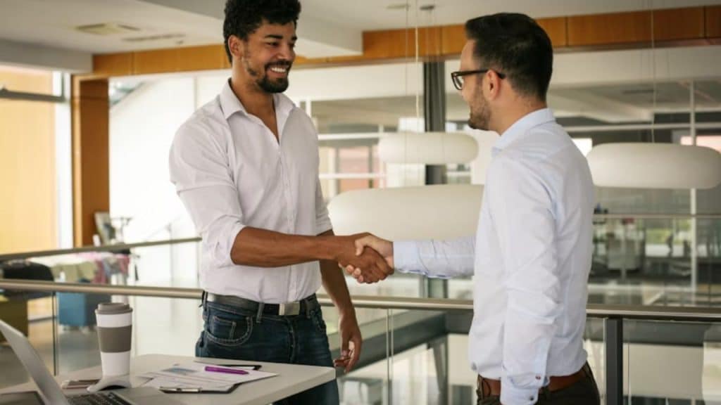 Man in office attire shaking hands and making eye contact with a colleague