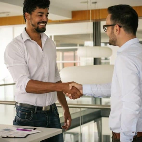 Man in office attire shaking hands and making eye contact with a colleague