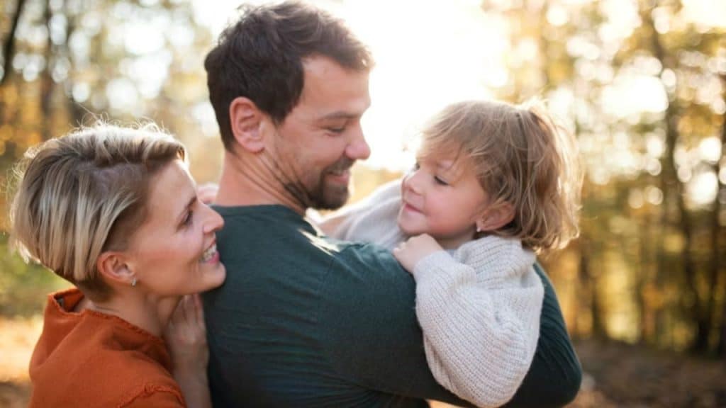 Loving father embracing his partner and child, symbolizing unity and emotional leadership