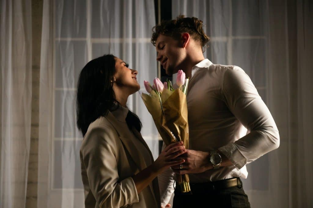 A man holding a flower for a woman