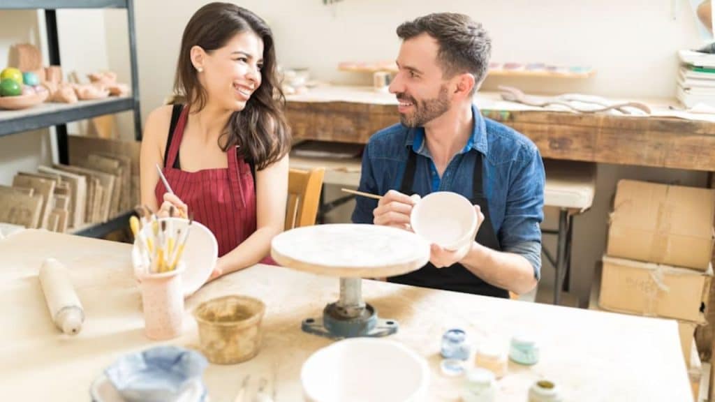 Couple enjoying a fun new anniversary activity like a pottery making class.
