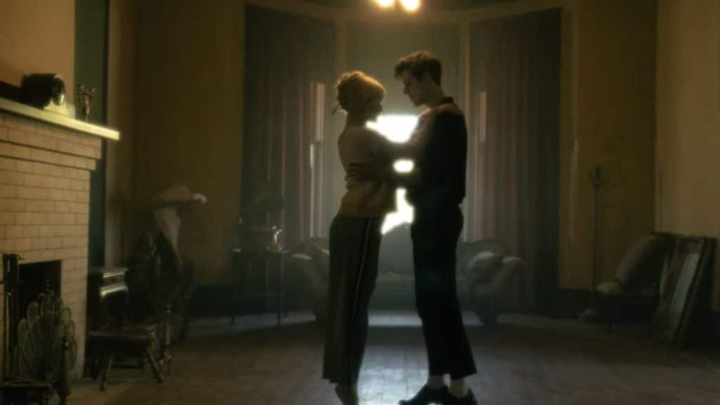 Couple slow dancing in a cozy living room with a curated playlist playing.