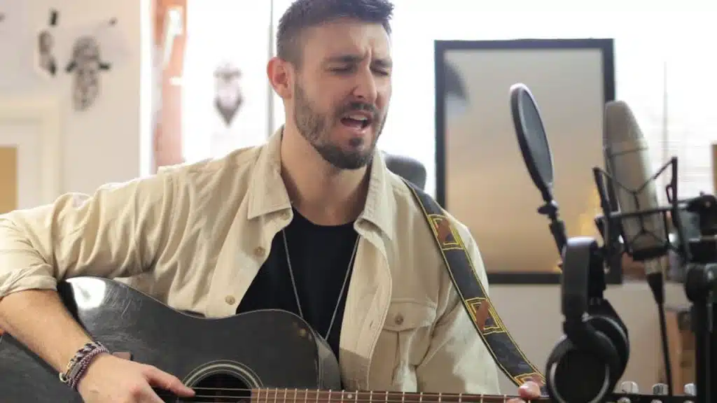 Man playing guitar and singing alone in a living room.