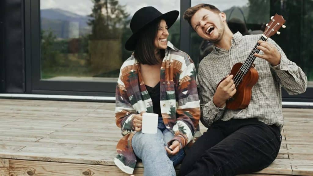 Couple laughing while trying an unfamiliar activity like singing with a ukulele.