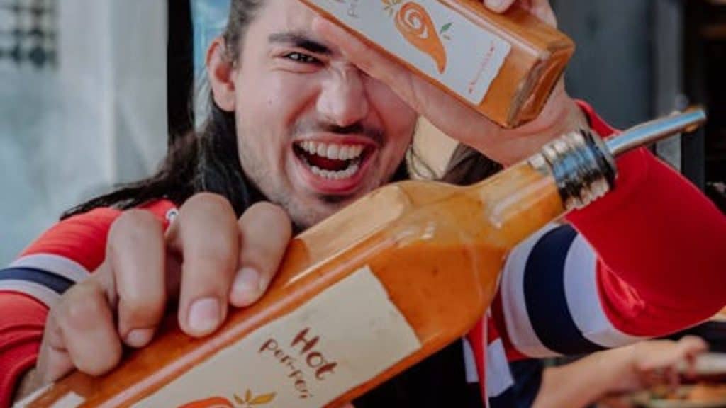 A man showing bottles of spicy sauce in a cafe