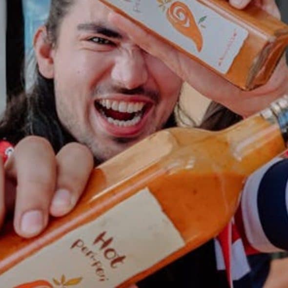 A man showing bottles of spicy sauce in a cafe