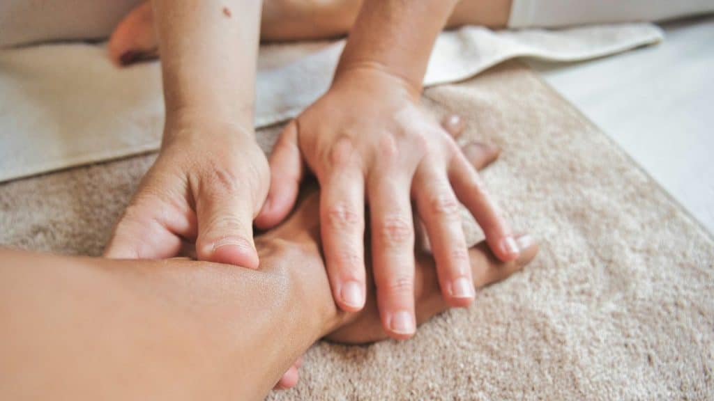A pair of hands massages another person's hand, resting on a textured towel.