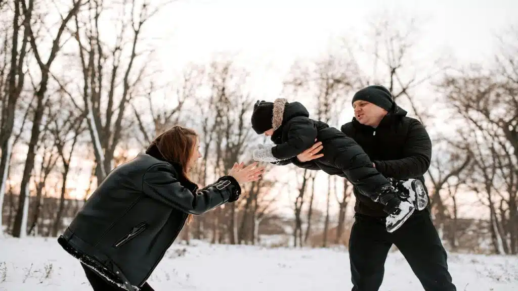 Parents playing with their kid in the snow.