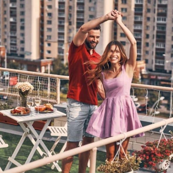 A confident man dancing calmly with his partner on a rooftop.