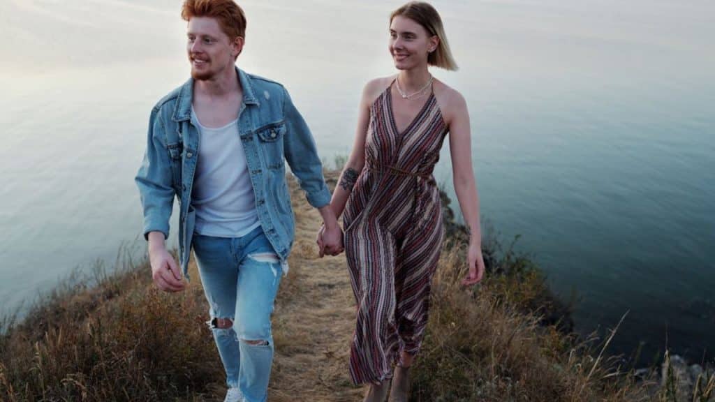 Man smiling calmly while holding hands with his partner during a quiet walk.