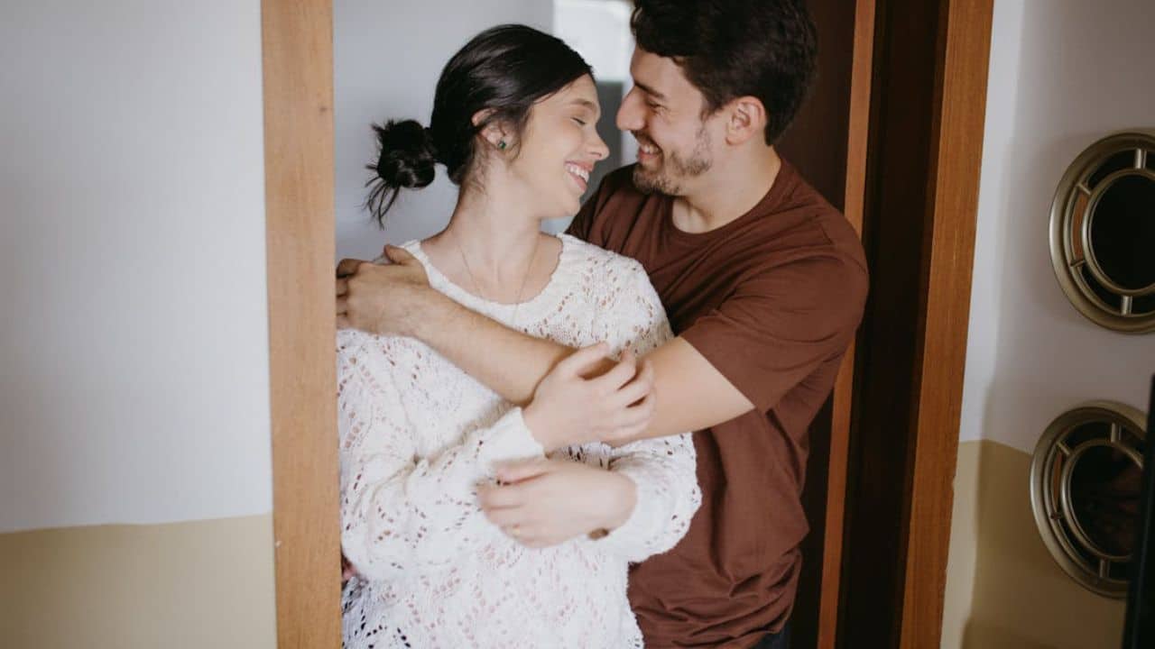 Woman heading out with a smile while her partner supports her from the doorway.
