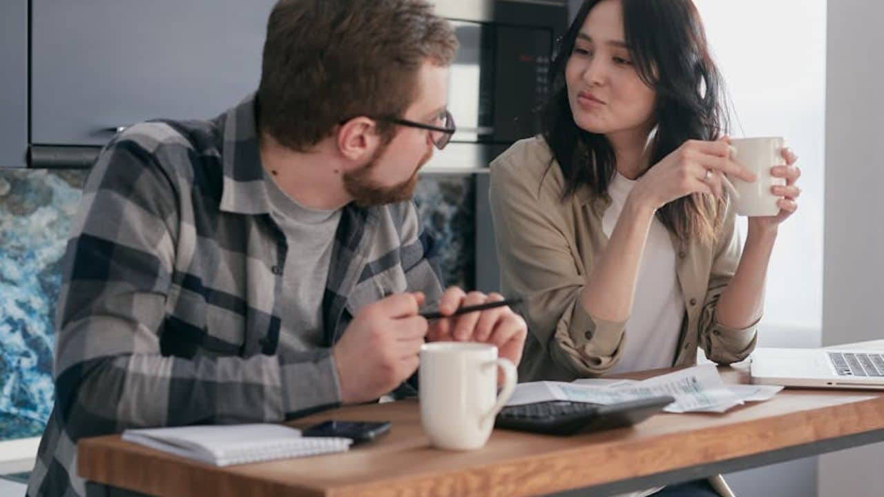 Couple discussing plans over coffee with a calendar and notebook open.