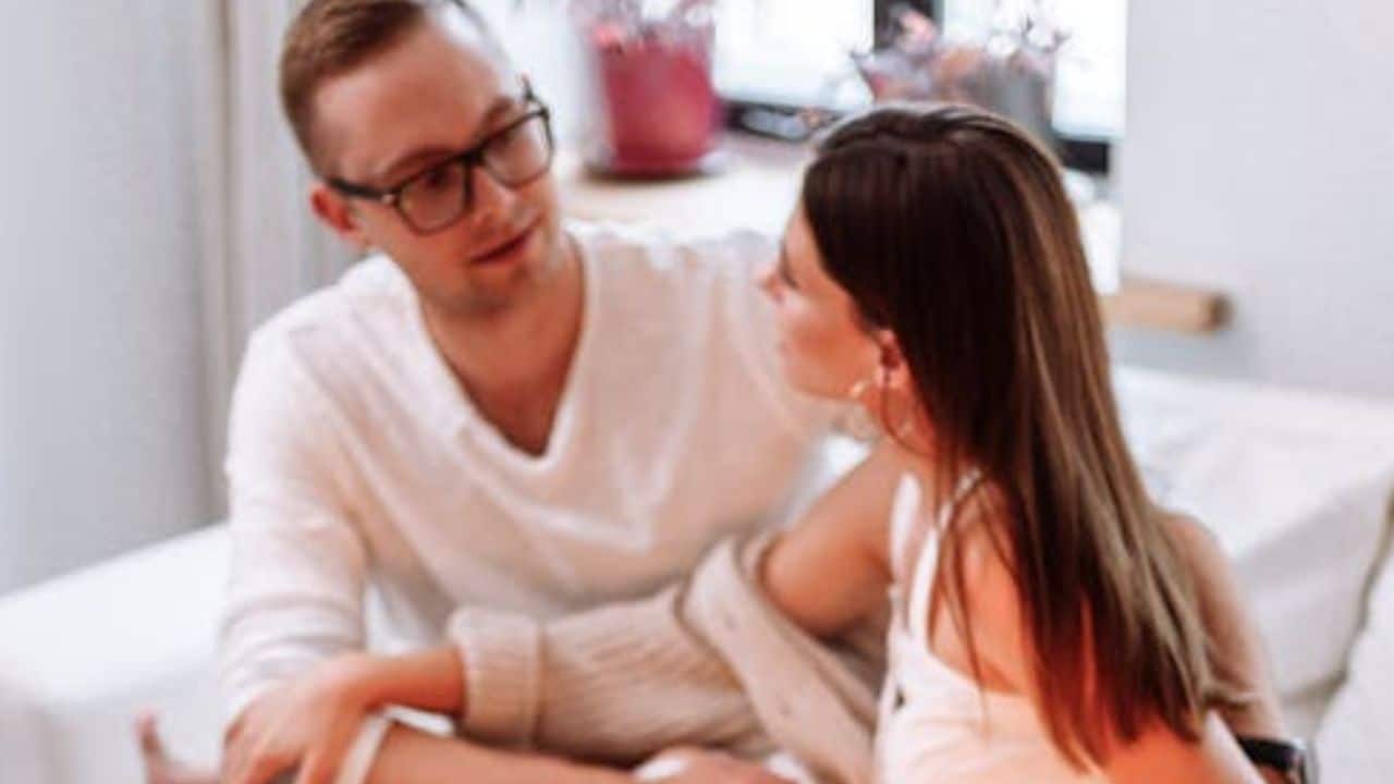 ALT Text: Man talking openly with his partner on a couch during a quiet evening.