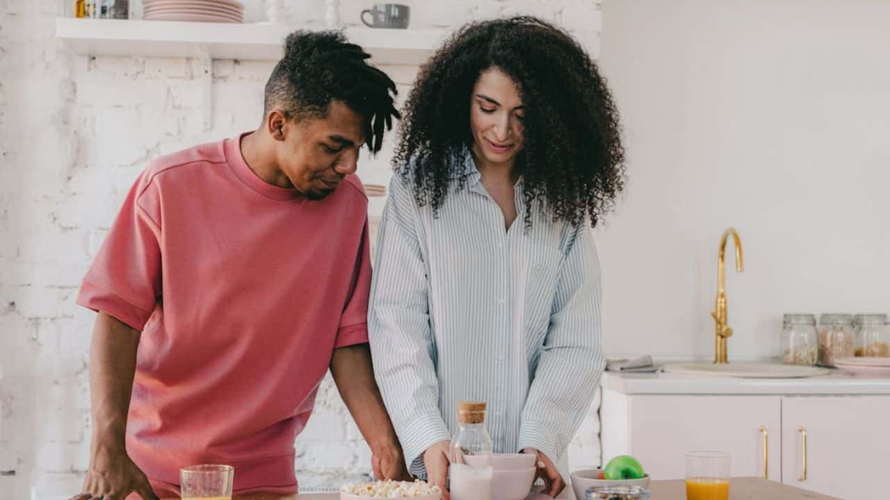 Man smiling and complimenting his partner while setting the table.