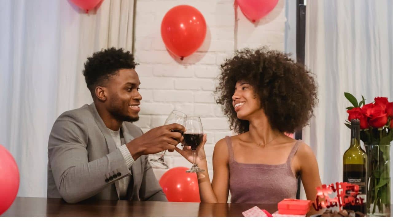Couple toasting at home with balloons and flowers.