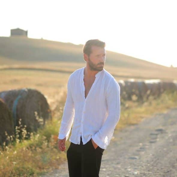 A man standing alone on a quiet street at sunset, deep in thought.