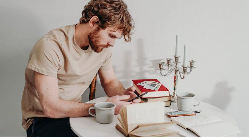 Man composing a thoughtful message on his phone in a calm setting.