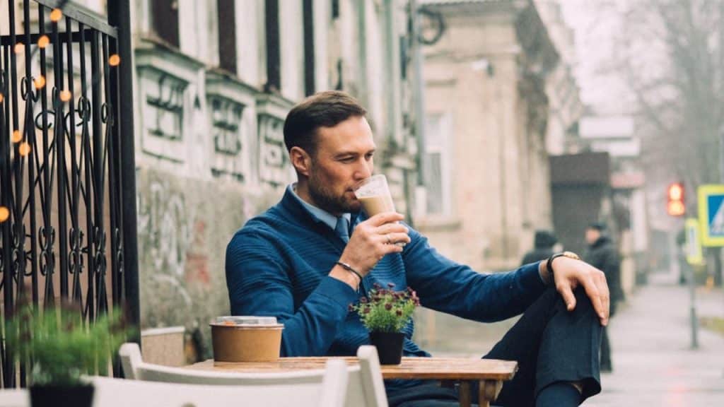 Man arriving on time and waiting patiently while drinking at a coffee shop.