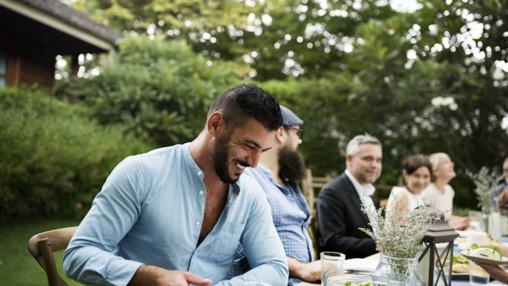 Man smiling but declining to discuss relationship details with mutual friends at a casual gathering.