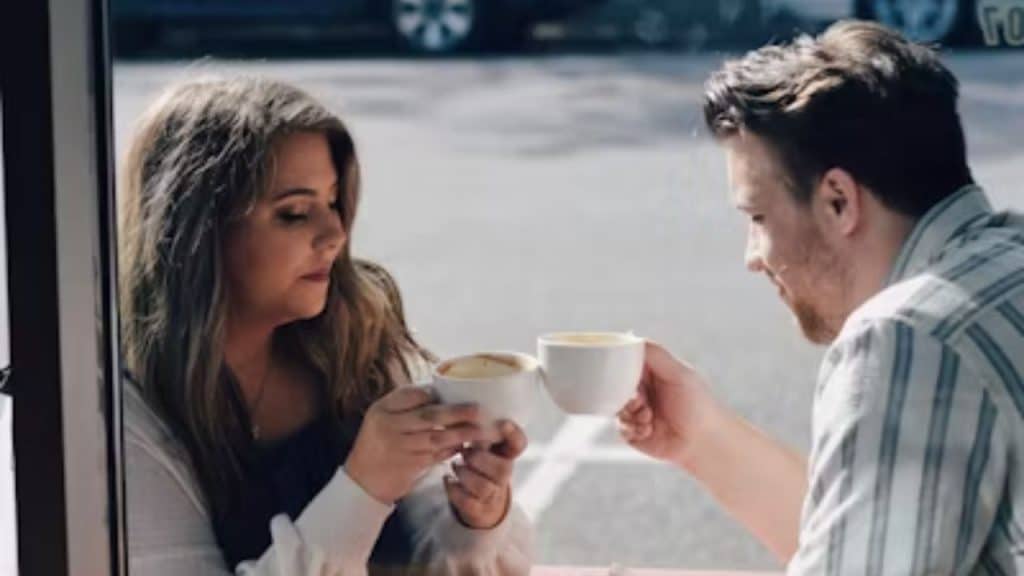 Couple holding coffee cups and sitting across from each other at a new café.