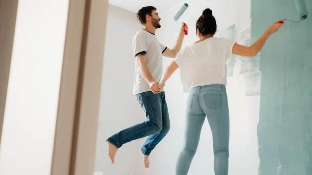 Couple painting a new space together, smiling and enjoying the moment.