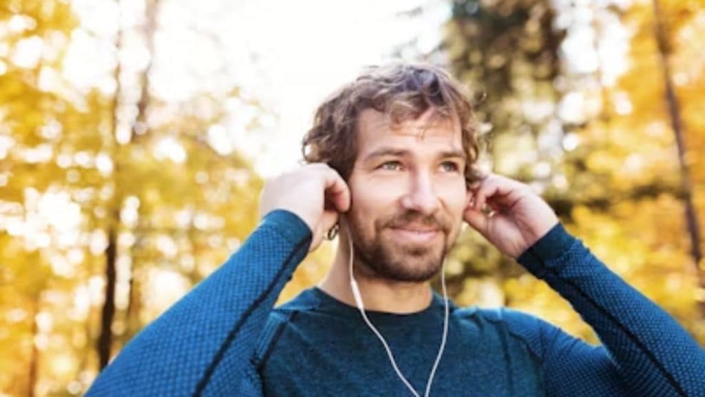 A man in his 40s walking confidently through a park at golden hour.