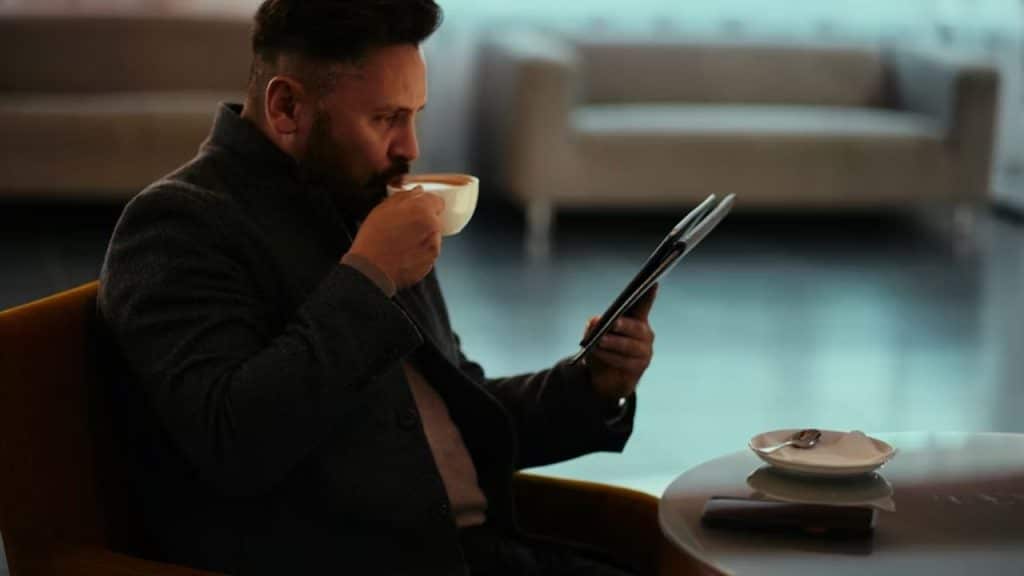 Man contentedly sipping coffee alone while reading his journal.